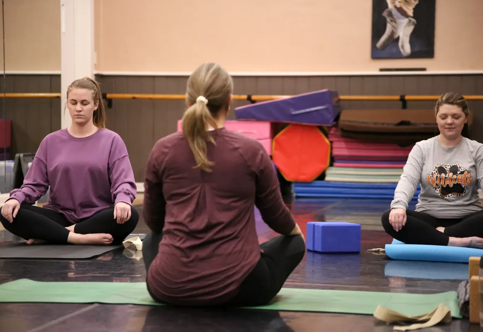 Adults seated cross-legged on yoga mats in a circle around their instructor in the Elevate studio
