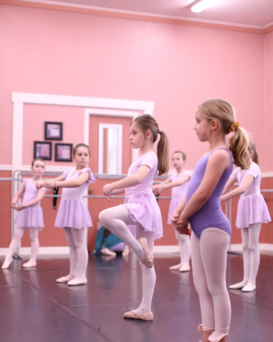 A young ballet dancer holding a retire position in class