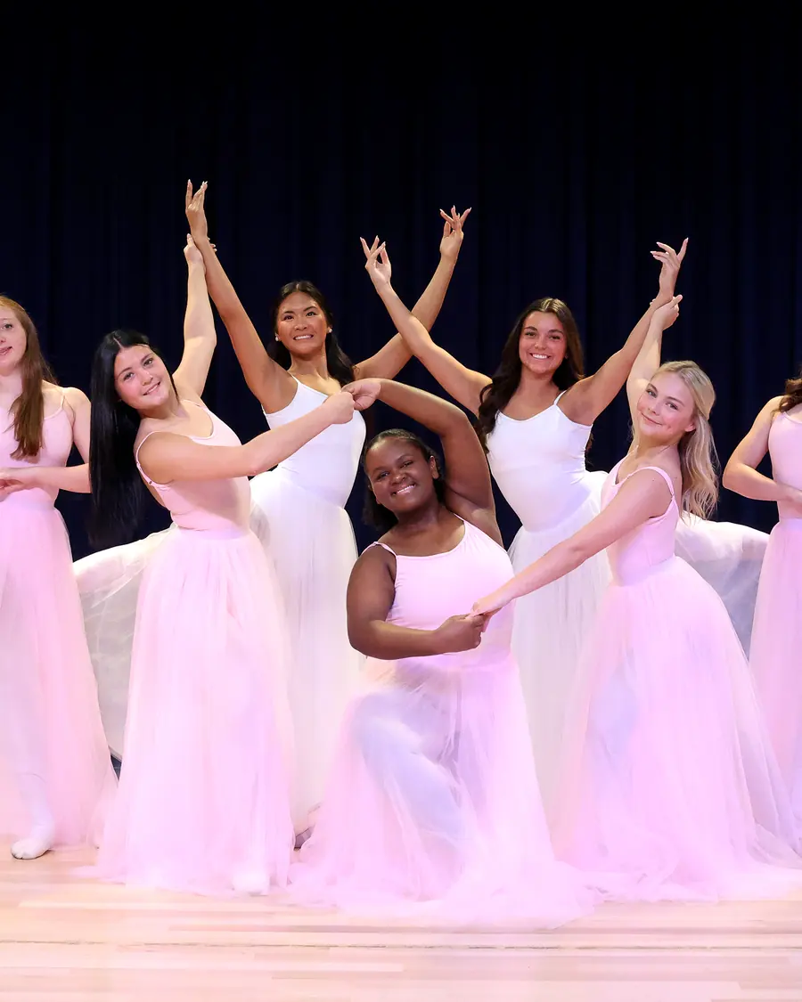 Elevate dancers in pale gowns posed together on the showcase stage