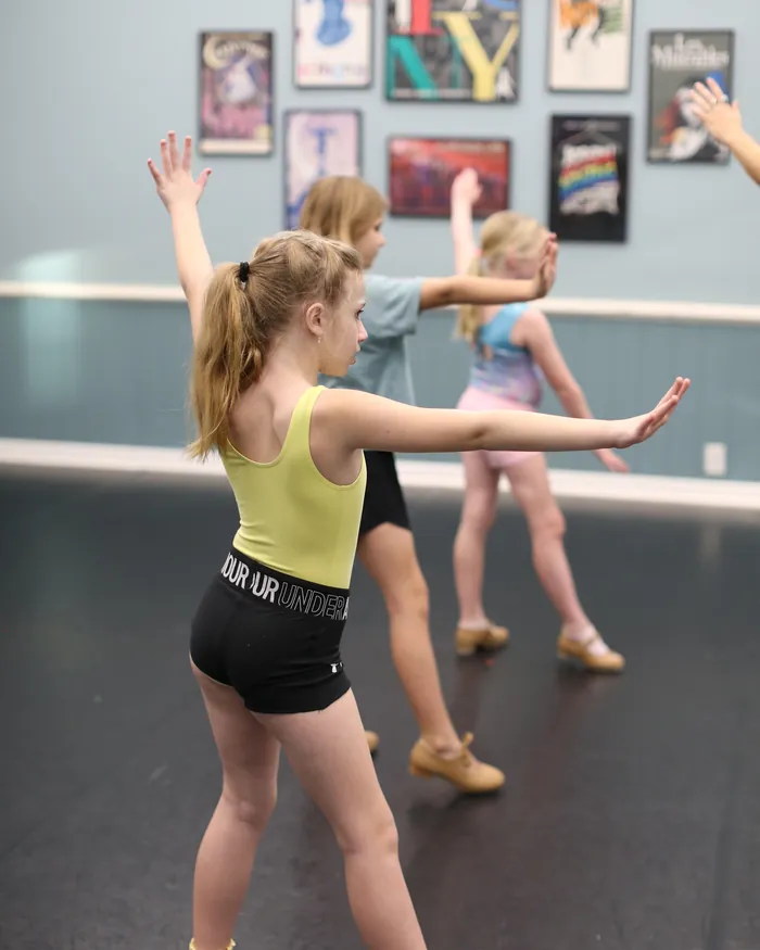 Tap dancers working through a combination together, arms reaching forward