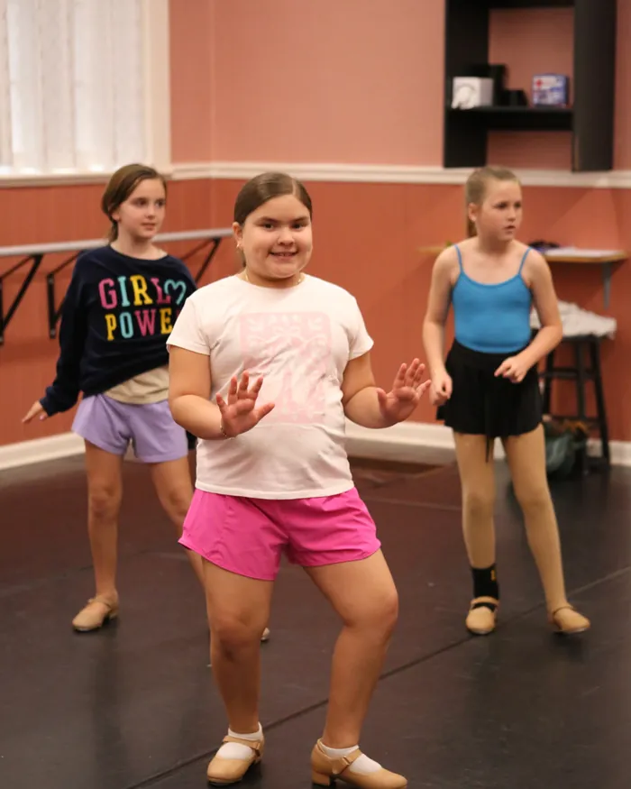 Tap dancers smiling as they work through a step together