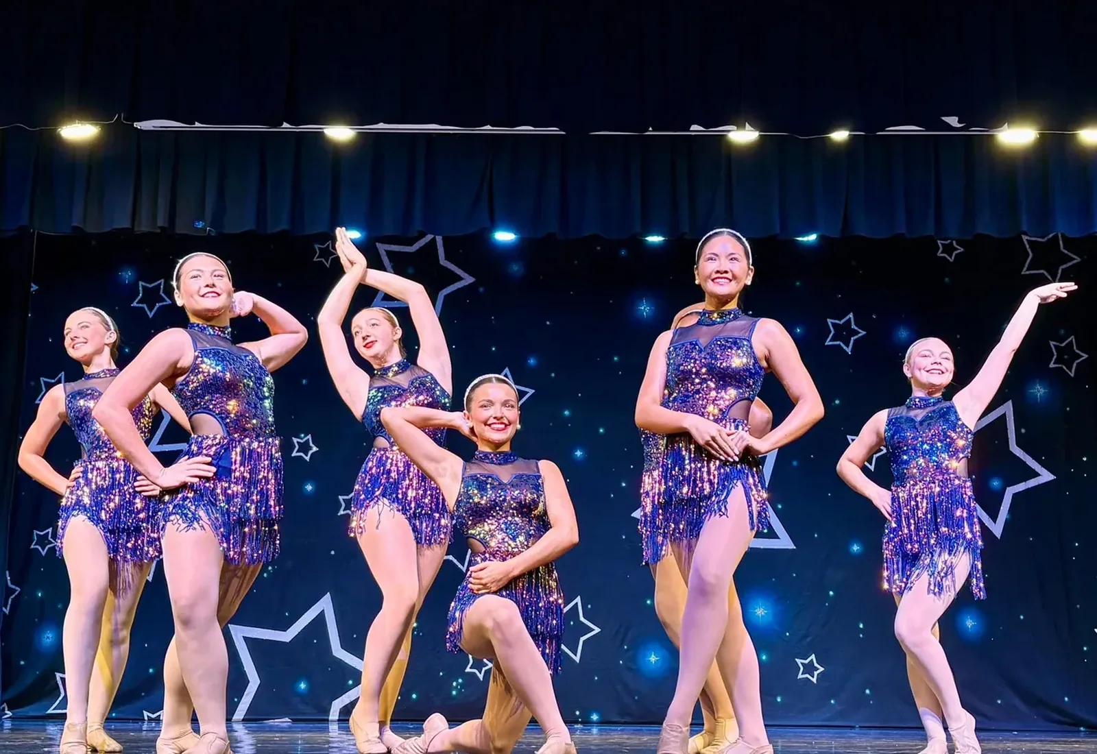 Elevate teen dancers in sequinned costumes performing together on the showcase stage