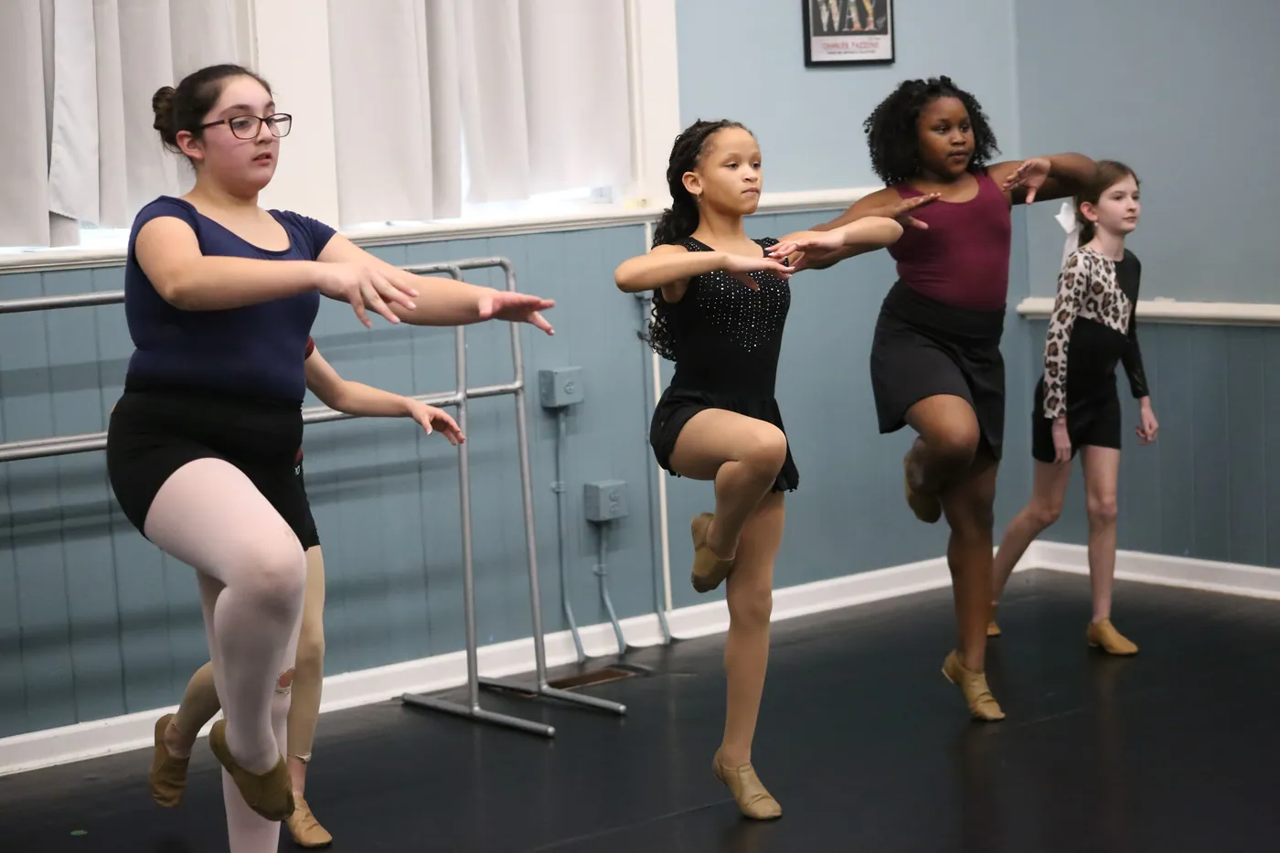 Jazz dancers balancing in a passe with their arms held forward